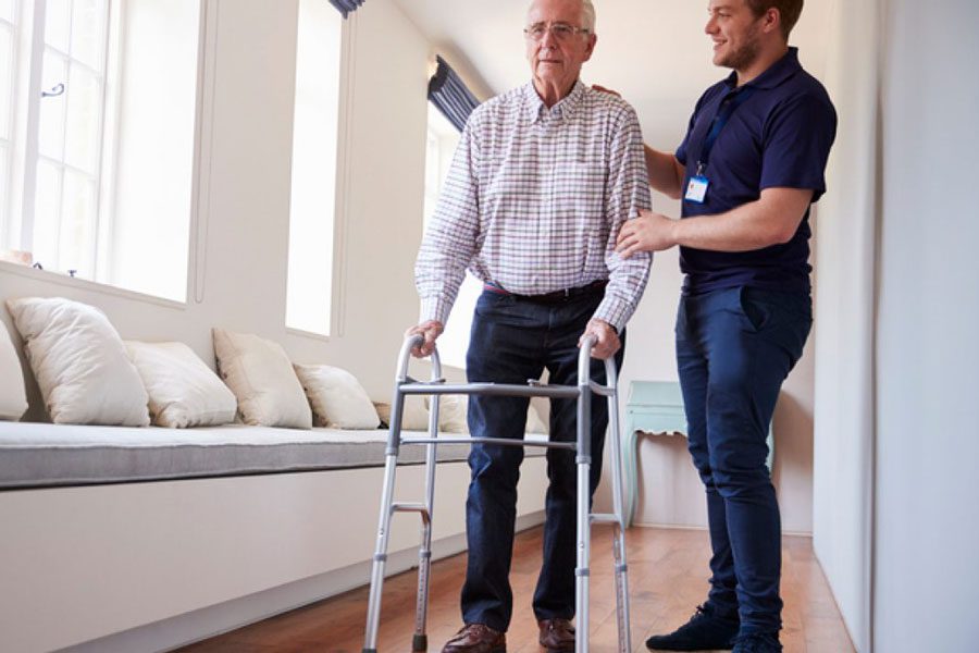 Senior man walking with assistance in hallway